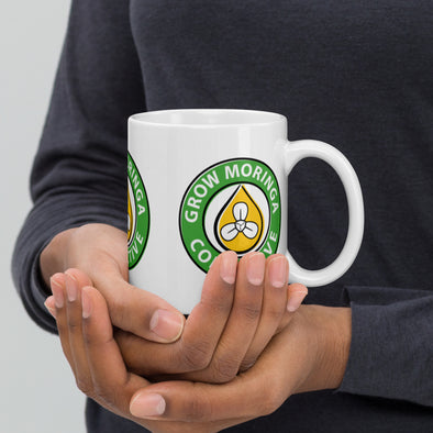 Woman cupping Coffee Mug with Grow Moringa Logo on both sides of the Mug.